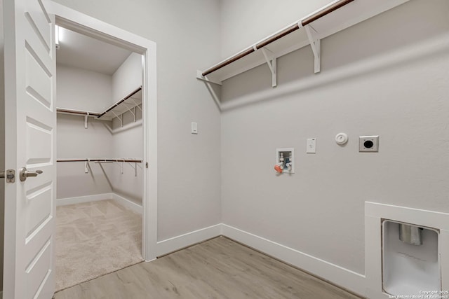 washroom featuring washer hookup, hookup for an electric dryer, gas dryer hookup, and light hardwood / wood-style flooring