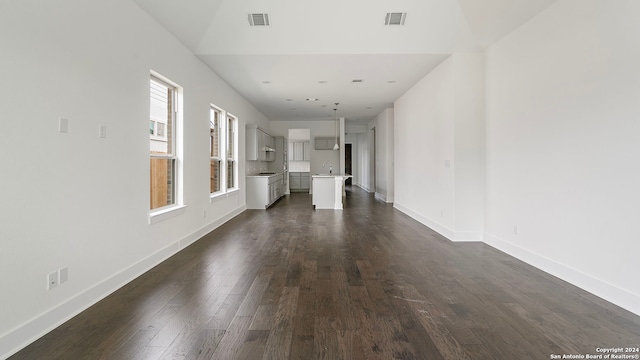 unfurnished living room featuring sink, dark hardwood / wood-style floors, and lofted ceiling