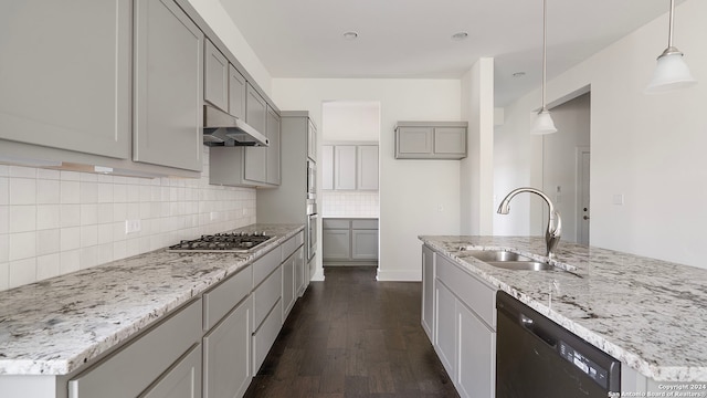 kitchen with black dishwasher, pendant lighting, a center island with sink, and sink