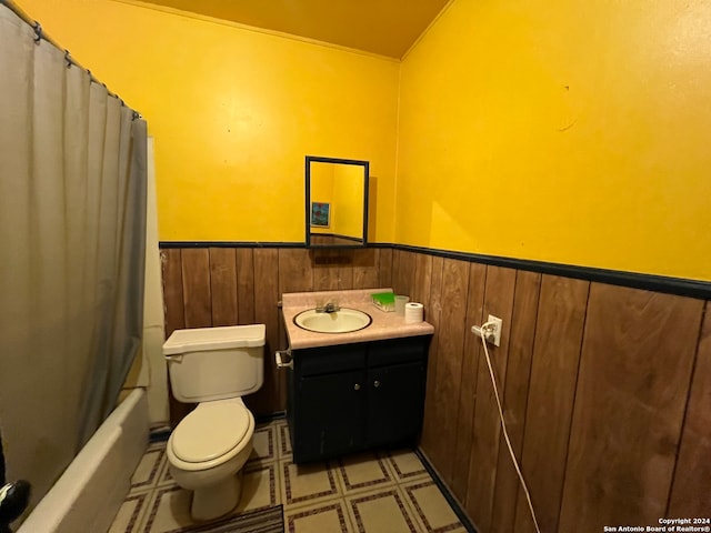 full bathroom featuring wooden walls, toilet, shower / tub combo, and vanity