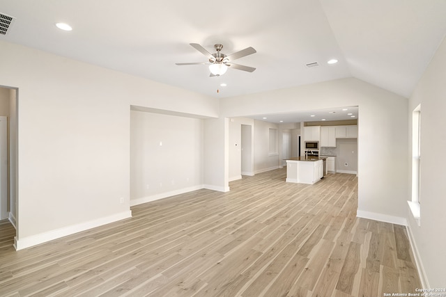 unfurnished living room with ceiling fan, vaulted ceiling, and light wood-type flooring