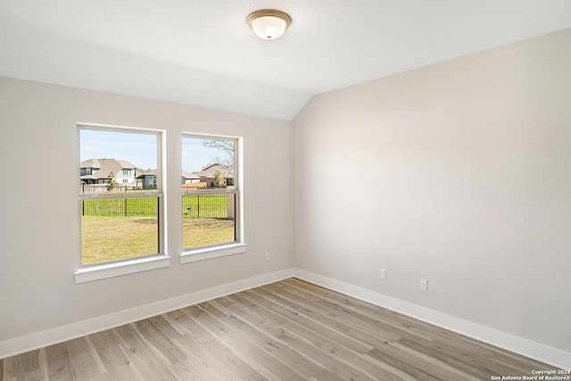 unfurnished room with vaulted ceiling and light hardwood / wood-style flooring