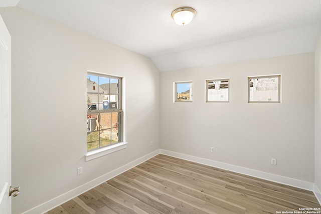 unfurnished room featuring hardwood / wood-style floors and vaulted ceiling