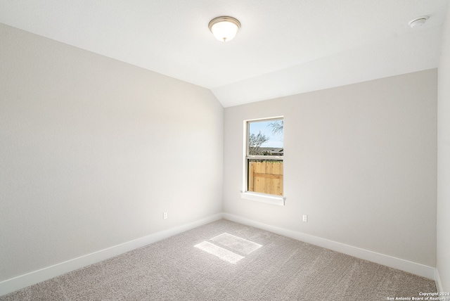 carpeted spare room with lofted ceiling