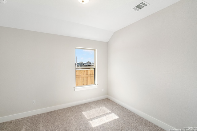 spare room featuring lofted ceiling and carpet