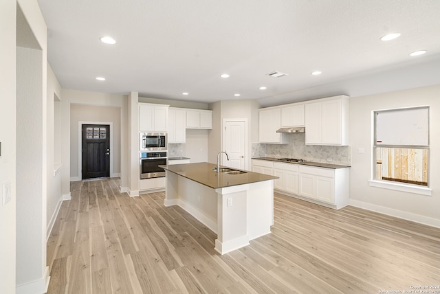 kitchen with a kitchen island with sink, light hardwood / wood-style flooring, stainless steel appliances, and white cabinets