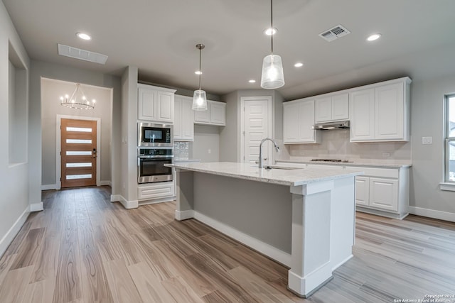 kitchen featuring appliances with stainless steel finishes, a sink, under cabinet range hood, white cabinets, and decorative backsplash
