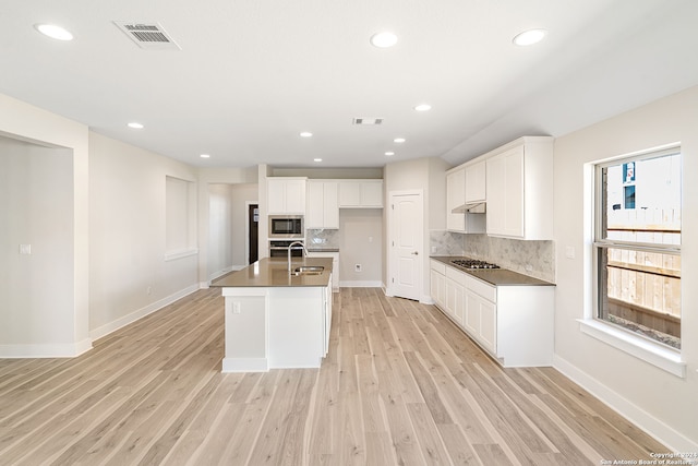 kitchen featuring light hardwood / wood-style floors, appliances with stainless steel finishes, an island with sink, and white cabinets