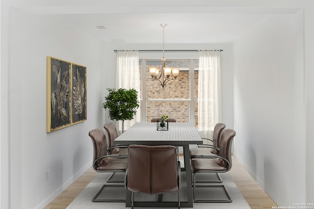 dining area with light wood-type flooring and an inviting chandelier