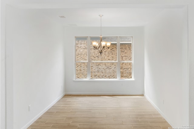 unfurnished dining area with light wood-type flooring and a chandelier