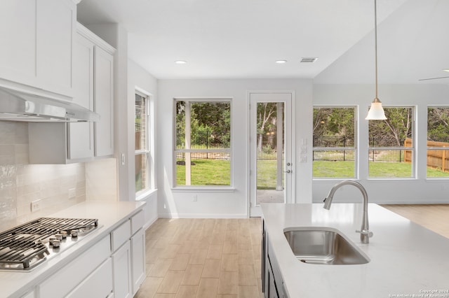 kitchen with pendant lighting, sink, stainless steel gas cooktop, white cabinetry, and light hardwood / wood-style floors