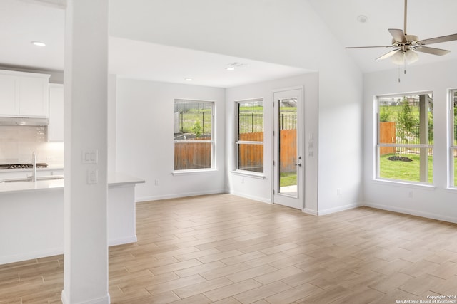 empty room with ceiling fan, sink, light hardwood / wood-style flooring, and vaulted ceiling