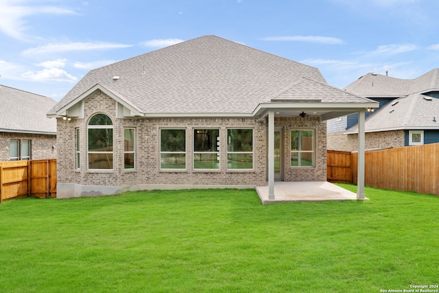 rear view of property with ceiling fan, a patio, and a lawn