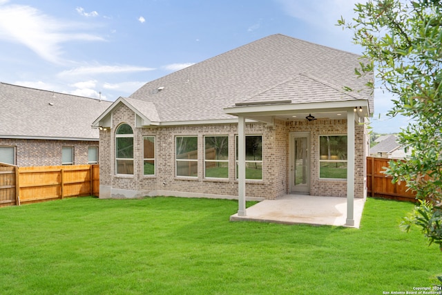 rear view of property featuring ceiling fan, a lawn, and a patio