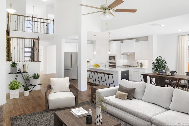 living room with a towering ceiling, dark hardwood / wood-style flooring, and ceiling fan