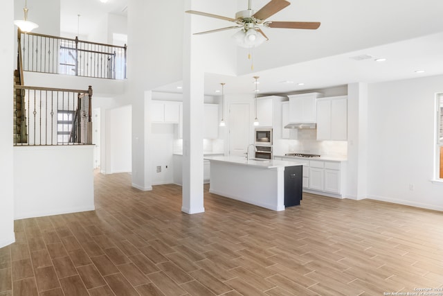 kitchen featuring stainless steel appliances, a high ceiling, light hardwood / wood-style flooring, and white cabinetry