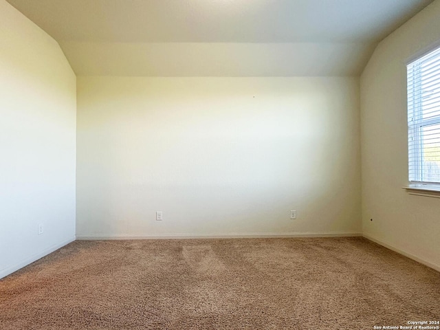 empty room featuring carpet floors and vaulted ceiling