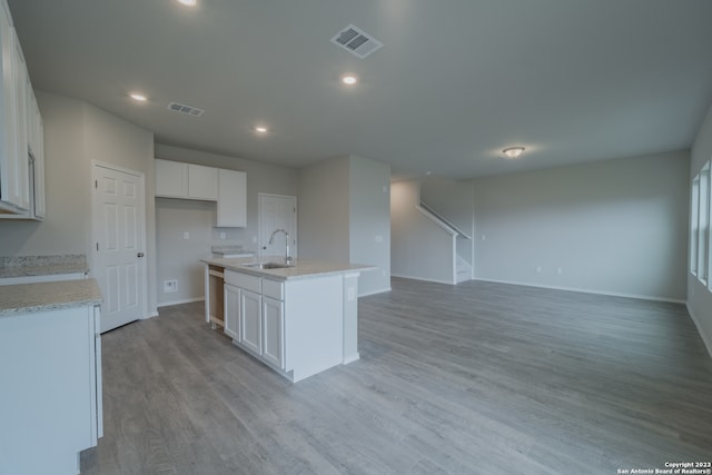 kitchen featuring white cabinets, an island with sink, light wood-type flooring, and sink