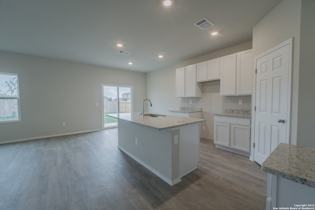 kitchen featuring an island with sink, white cabinets, sink, and light hardwood / wood-style floors