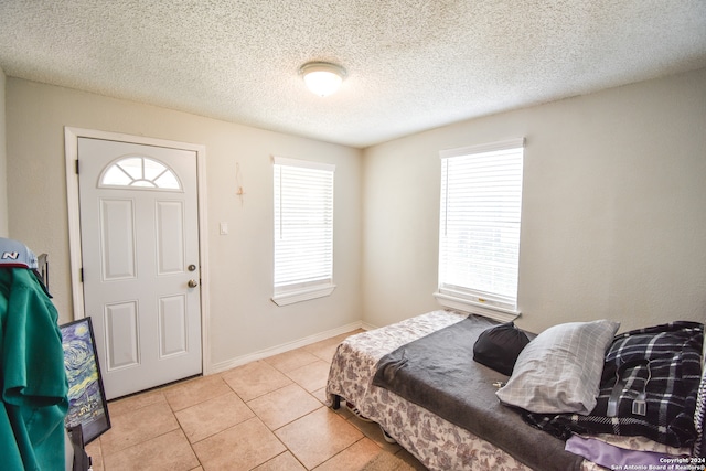 bedroom featuring a textured ceiling, light tile patterned floors, and multiple windows