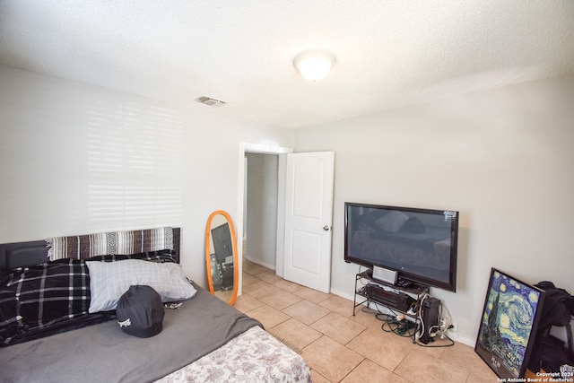 bedroom featuring light tile patterned floors and a textured ceiling