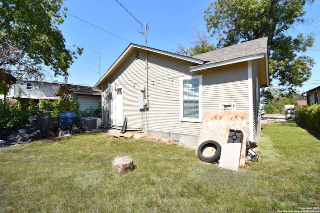 rear view of house featuring a lawn and central AC