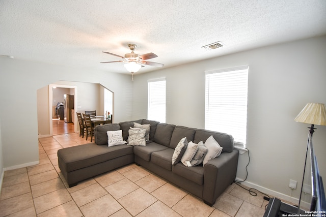 tiled living room featuring ceiling fan and a textured ceiling