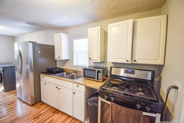 kitchen with light hardwood / wood-style floors, white cabinetry, sink, stainless steel appliances, and a textured ceiling