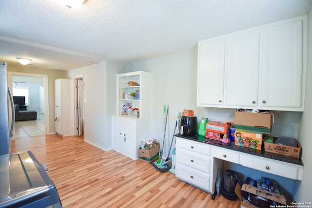 kitchen with white cabinets, light wood-type flooring, and a textured ceiling