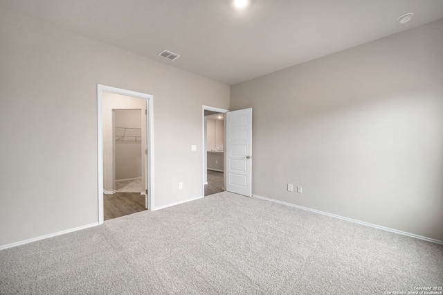 unfurnished bedroom featuring dark colored carpet, a closet, and a walk in closet