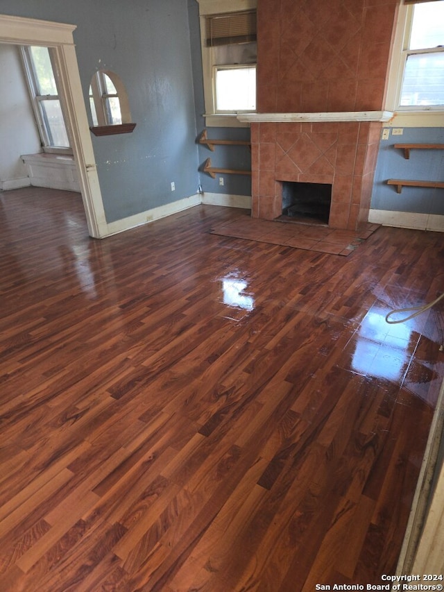 unfurnished living room with a fireplace, plenty of natural light, and dark hardwood / wood-style flooring