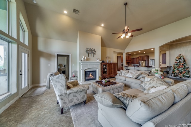 tiled living room with ceiling fan and high vaulted ceiling