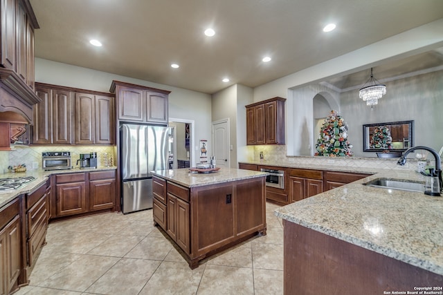 kitchen with hanging light fixtures, sink, a kitchen island, appliances with stainless steel finishes, and a notable chandelier