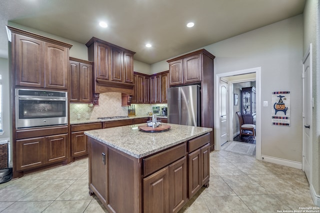 kitchen featuring appliances with stainless steel finishes, dark brown cabinets, a center island, and light tile patterned floors