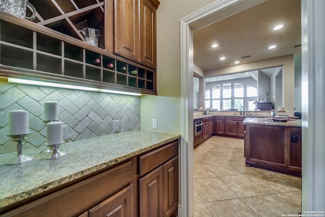 kitchen featuring light stone counters, light tile patterned flooring, sink, backsplash, and oven