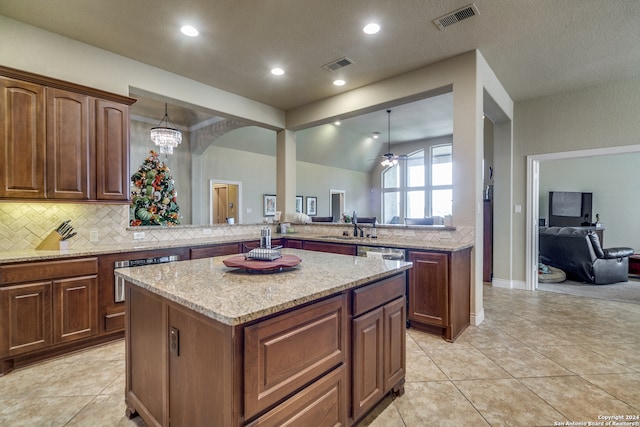 kitchen with pendant lighting, kitchen peninsula, ceiling fan with notable chandelier, and a kitchen island