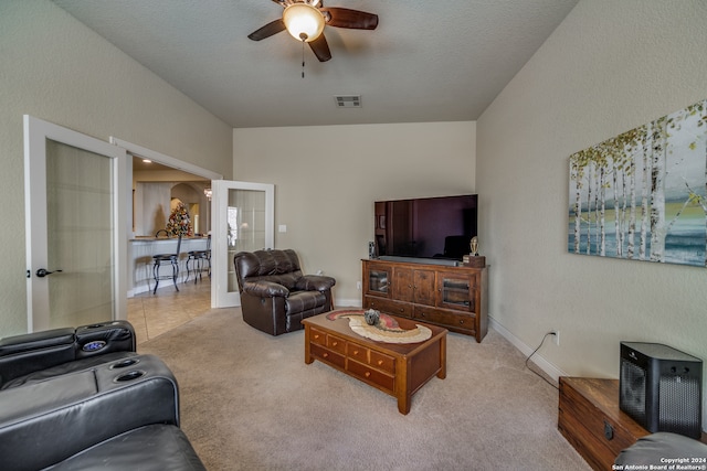 living room with ceiling fan, vaulted ceiling, french doors, and light colored carpet