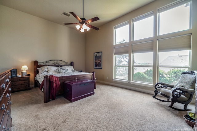 bedroom with ceiling fan, carpet flooring, and a high ceiling