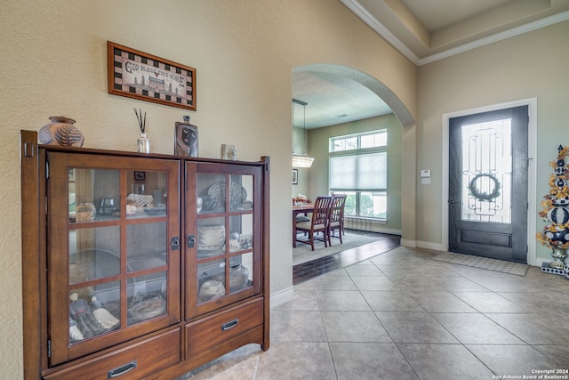 entryway featuring ornamental molding, a notable chandelier, light tile patterned floors, and a textured ceiling