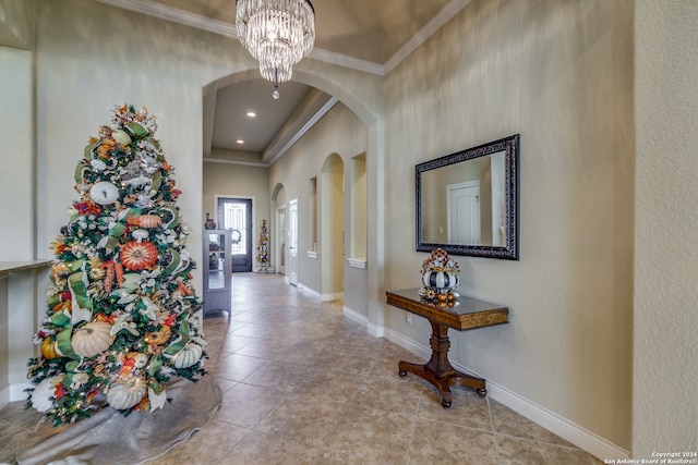 tiled foyer featuring an inviting chandelier and crown molding