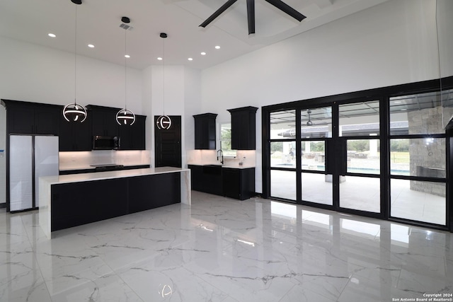 kitchen with freestanding refrigerator, a wealth of natural light, a towering ceiling, and dark cabinetry