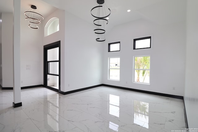 spare room with a notable chandelier and a towering ceiling