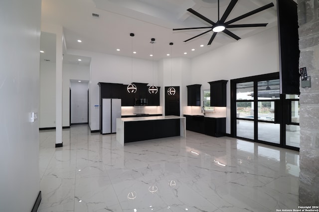 kitchen featuring a high ceiling, ceiling fan, sink, hanging light fixtures, and a center island