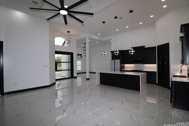 kitchen with a towering ceiling, pendant lighting, sink, and a center island