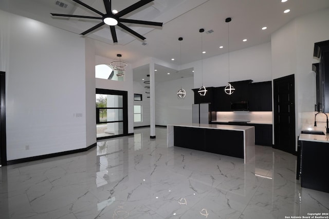 kitchen featuring a sink, dark cabinetry, a ceiling fan, a high ceiling, and black microwave