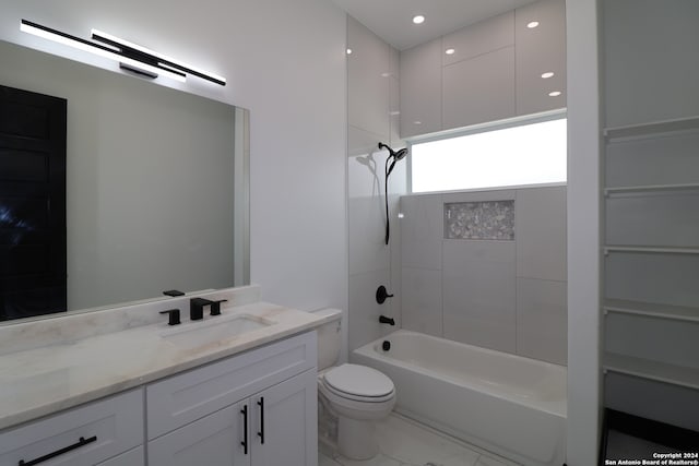 full bathroom featuring tiled shower / bath, vanity, and toilet