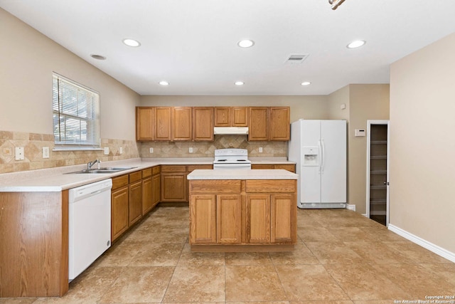 kitchen featuring tasteful backsplash, white appliances, sink, and a center island