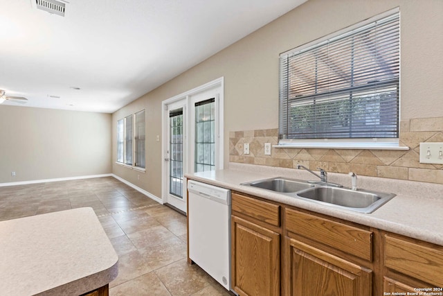 kitchen with decorative backsplash, light tile patterned flooring, sink, and white dishwasher