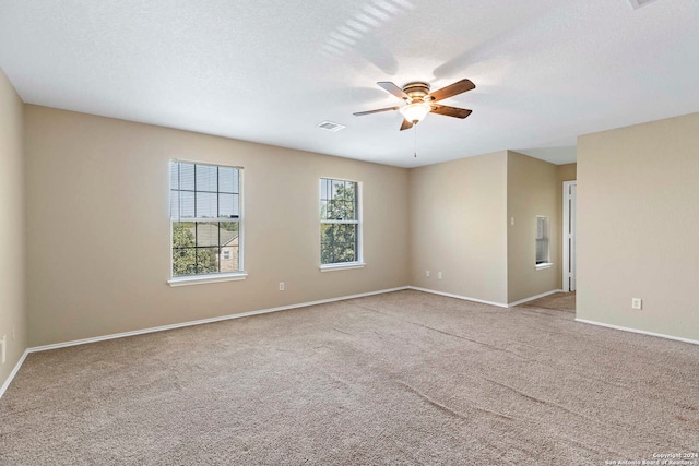 spare room with ceiling fan, a textured ceiling, and light carpet