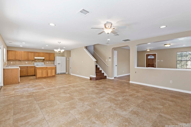 kitchen featuring decorative backsplash, white appliances, sink, ceiling fan with notable chandelier, and pendant lighting